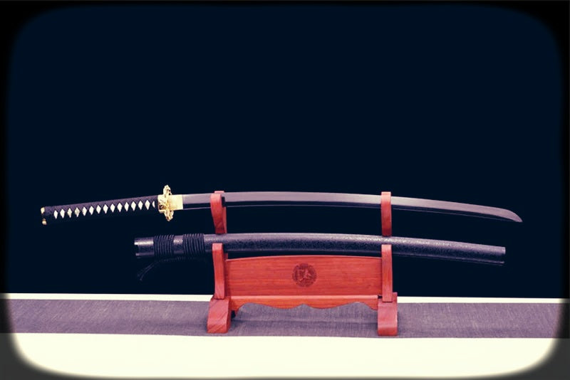 A Spring Steel Samurai Sword with a polished curved blade, black saya, white diamond-pattern handle wrap, and gold tsuba displayed on a wooden stand against a dark background.