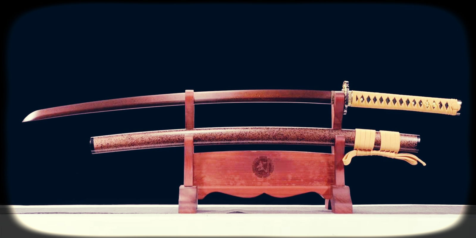 Wooden practice sword displayed on a wooden stand, with a matching scabbard, light-colored handle wrap, and cord tie, set against a dark background.